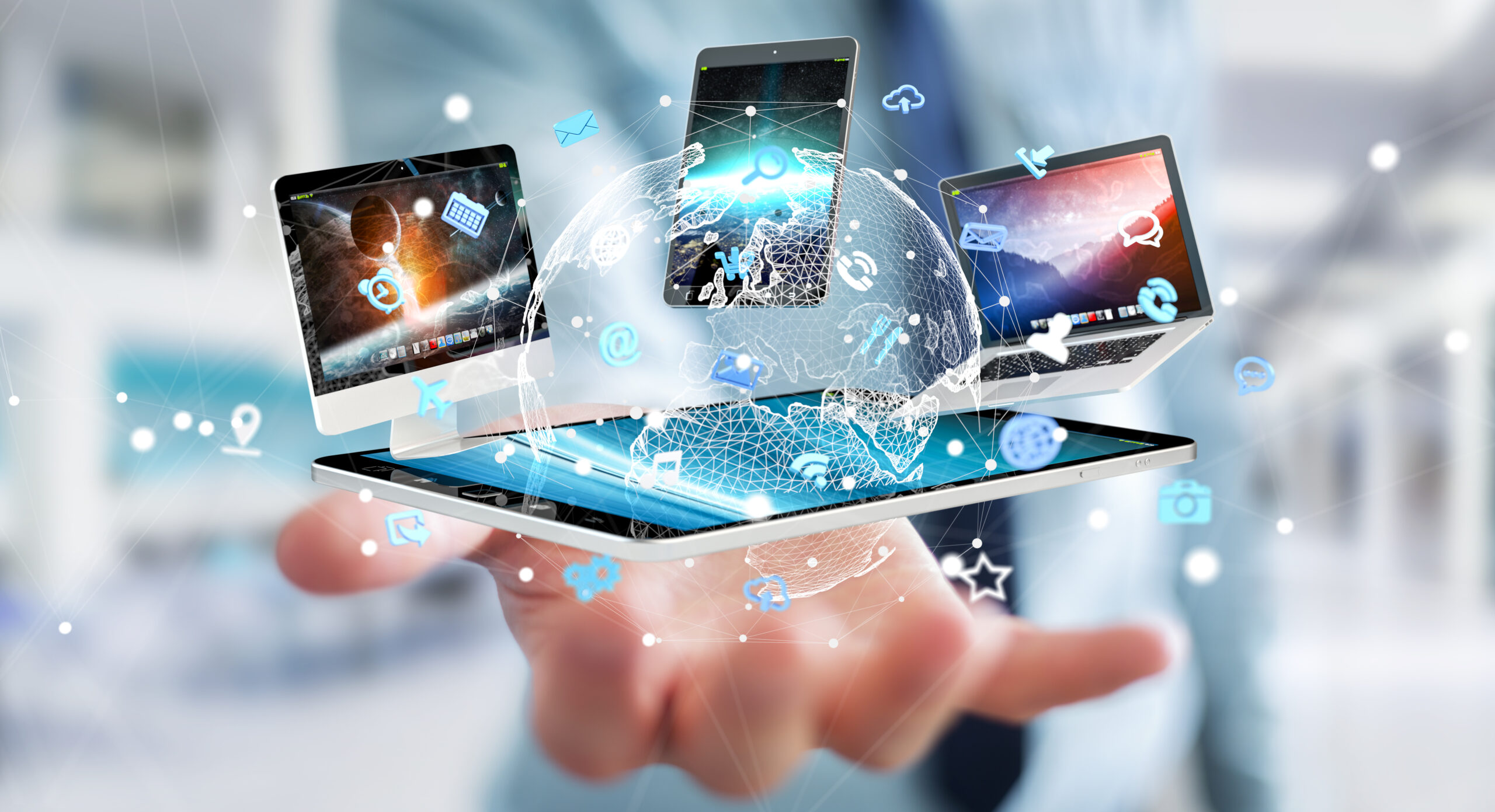Hand holding a tablet with connected digital devices, global network visualization, and communication icons representing modern consumer technology and smart devices